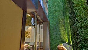 A courtyard with a long wooden bench seating area, a glass wall, and a vertical garden. - All Inn Hotel (Istanbul)