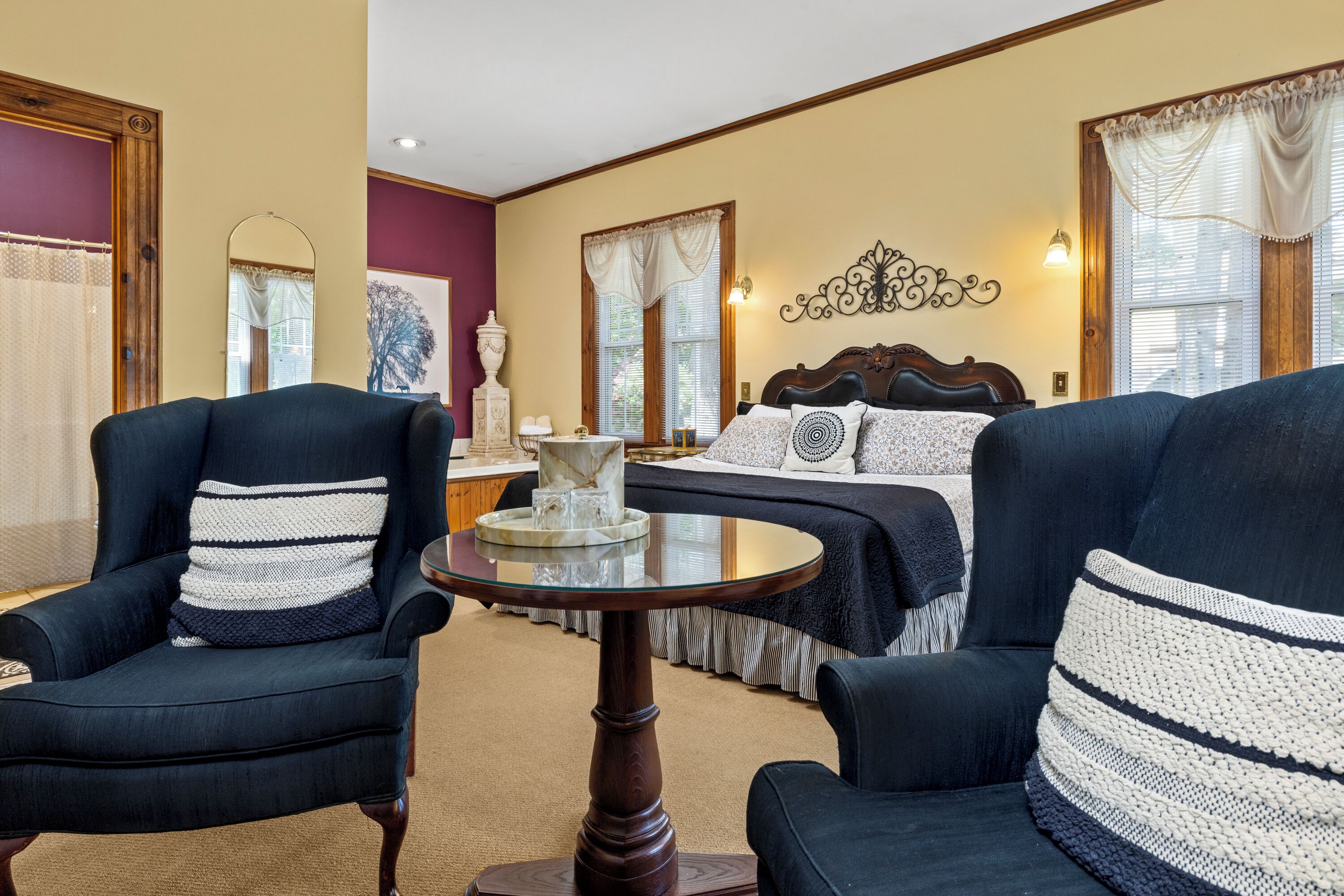 A hotel room with a bed, two armchairs, a round table, and a decorative wall piece.