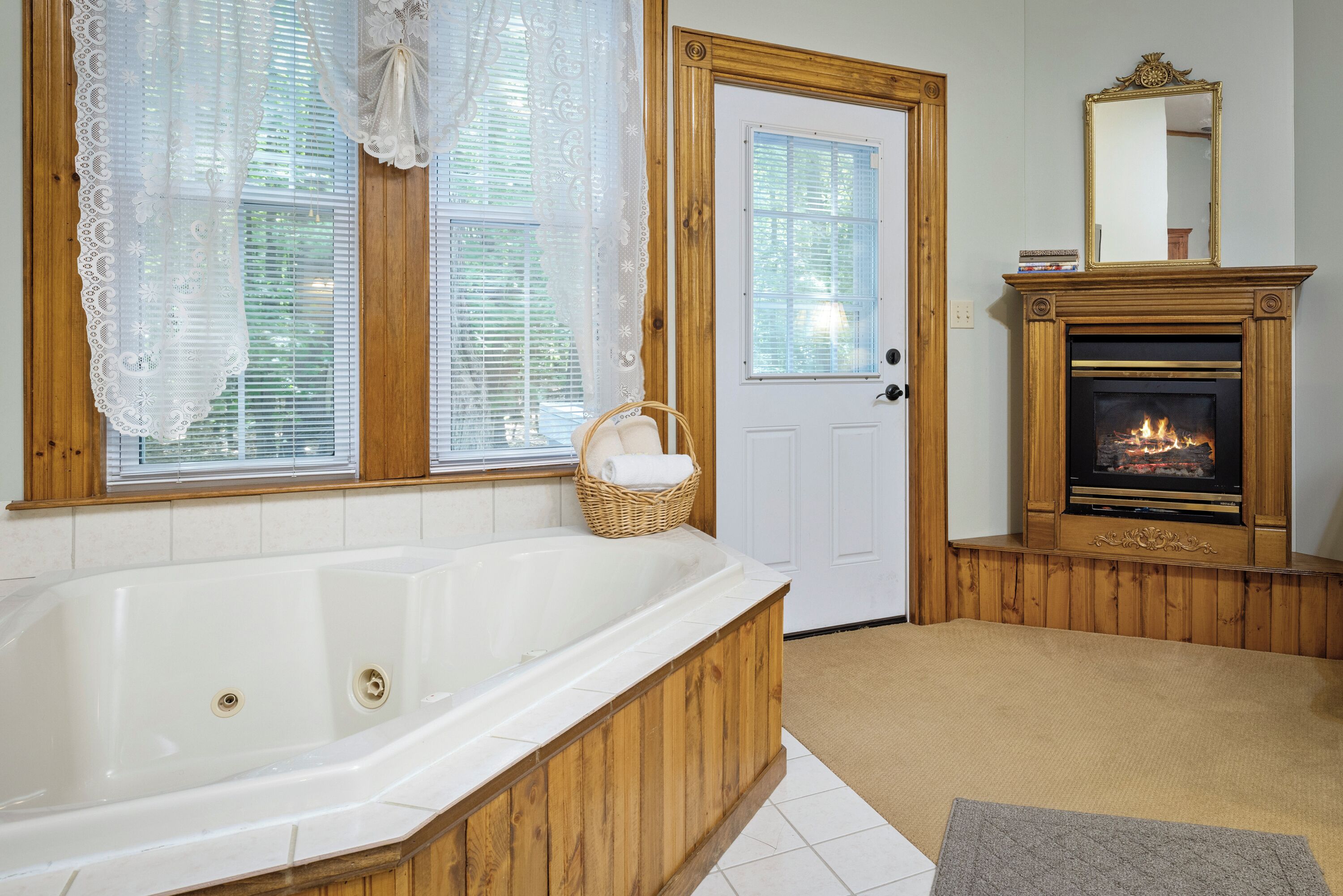 A bathroom with a freestanding bathtub, a wooden door, and a fireplace.