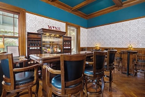 Eine Bar mit Holzmöbeln, einer Weinauslage und strukturierter Tapete.