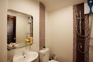 Un baño con estante de vidrio, inodoro, ducha y espejo.