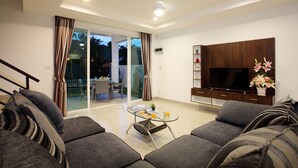 Een moderne woonkamer met een bank, een glazen salontafel en een flatscreen televisie.