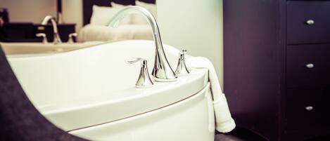 Ein modernes Badezimmer mit einer weißen Badewanne, einem einzelnen Wasserhahn und einem dunklen Holzschrank.