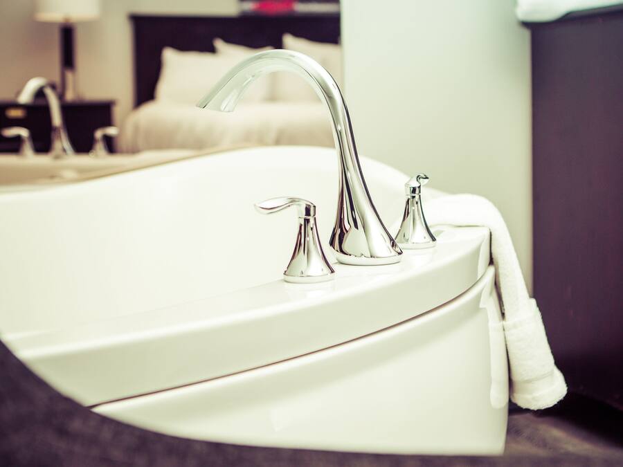 Un baño moderno con una bañera blanca, un solo grifo y un mueble de madera oscura.