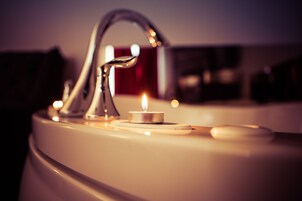 A bathroom sink with a modern faucet, a lit candle, and a soap dish.