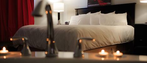 A hotel room with a bed, nightstands, a lamp, and candles.