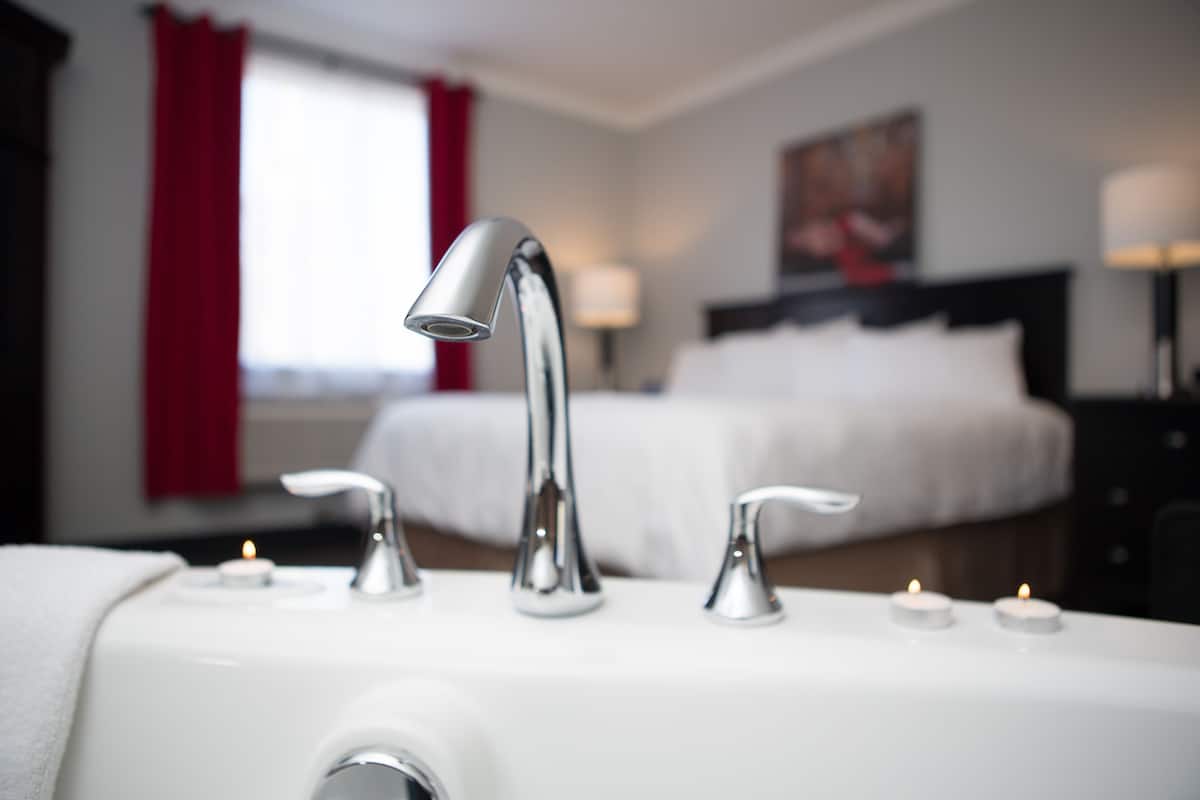 Et badeværelse på et hotel med en moderne vask, to vandhaner og to tændte stearinlys på bordet.