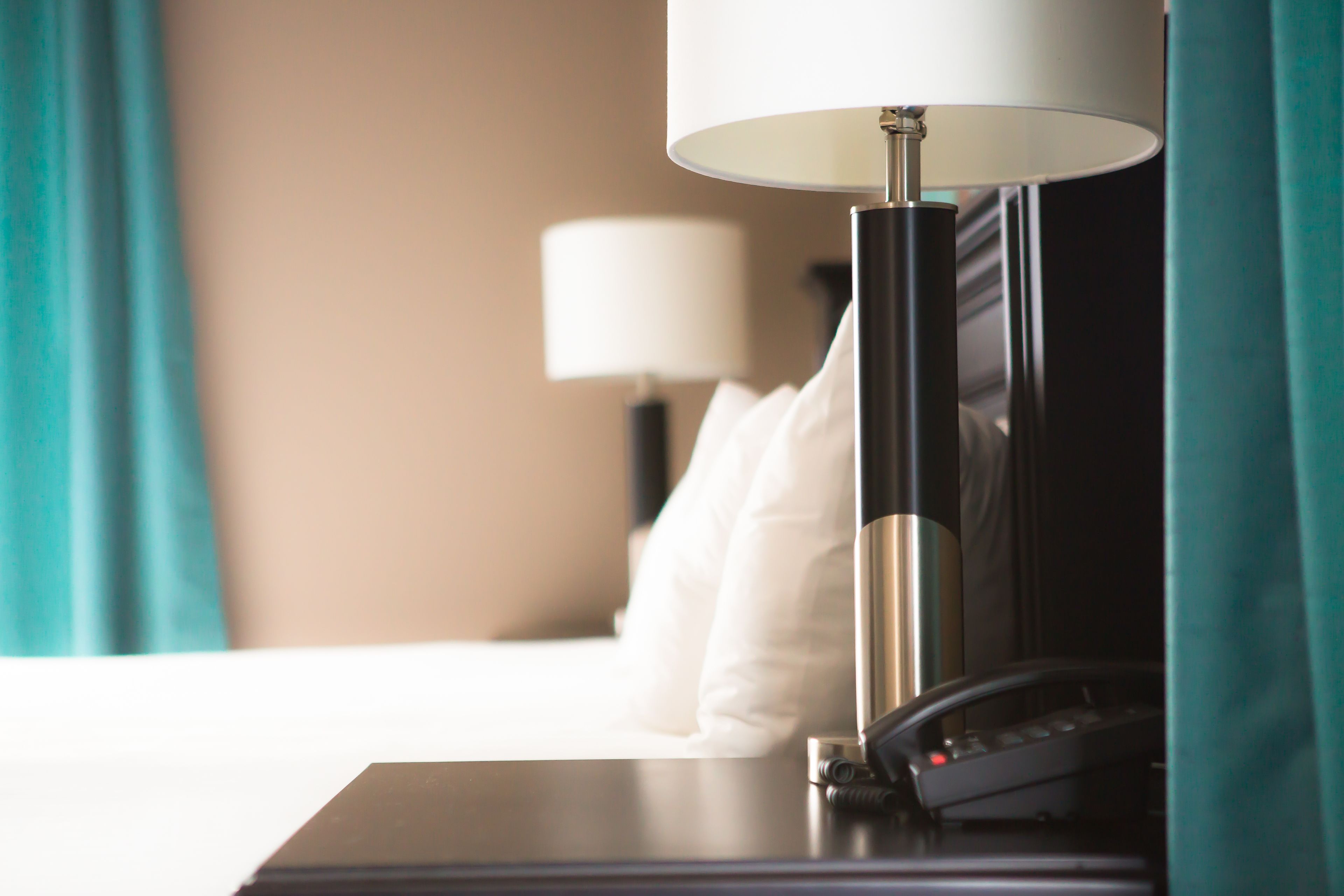 Een hotelkamer met een bed, een bedlamp en een telefoon.