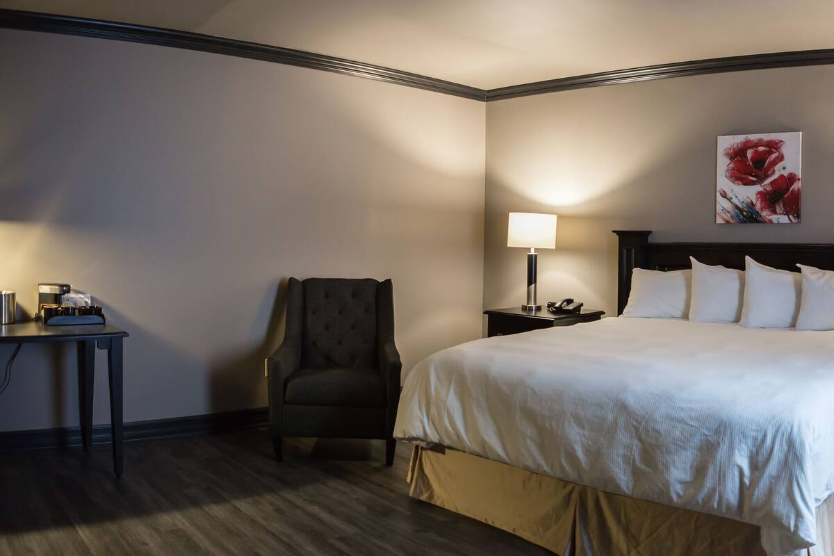 Et hotelværelse med en stor seng, to sengeborde med lamper, en stol og et skrivebord med lampe.
