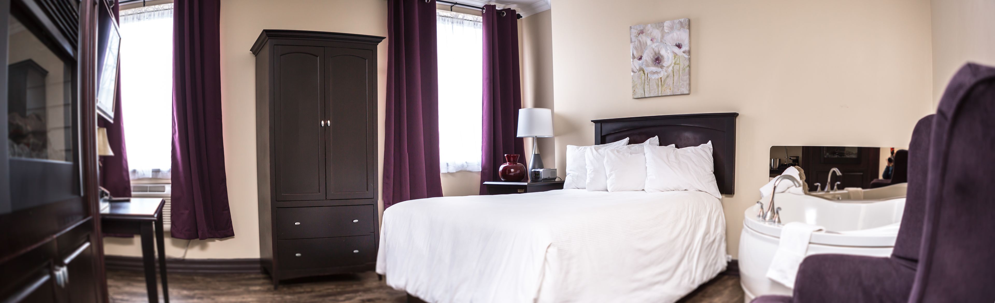 Una habitación de hotel con una cama grande, un armario, un escritorio y una silla.