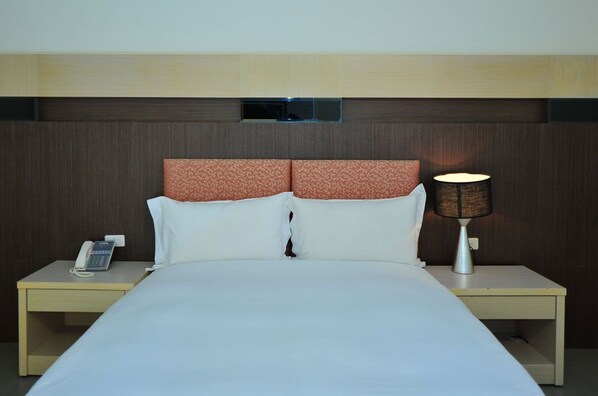A hotel room with a bed, two pillows, a bedside lamp, a nightstand, and a telephone. - Yake (Hengchun)