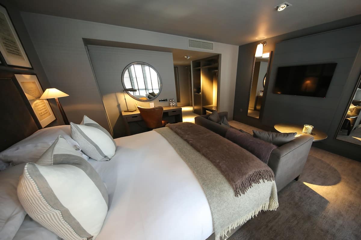 Una habitación de hotel moderna con una cama grande, un sofá, un escritorio y un televisor.
