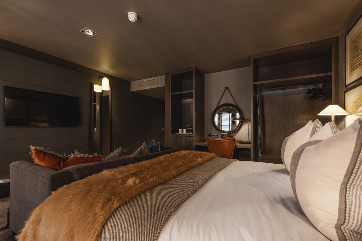 Una habitación de hotel moderna con una cama grande, un escritorio, un televisor y un espejo.