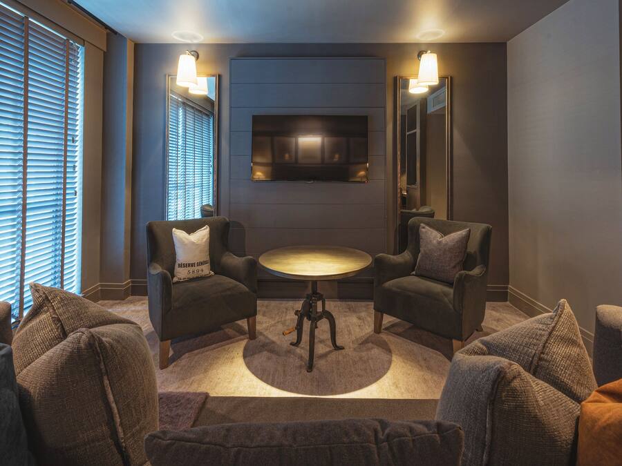 A modern lounge area with two armchairs, a small round table, and a television mounted on the wall.