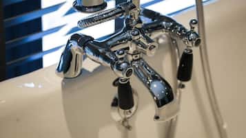 A chrome faucet with multiple handles and a hose, attached to a white sink.