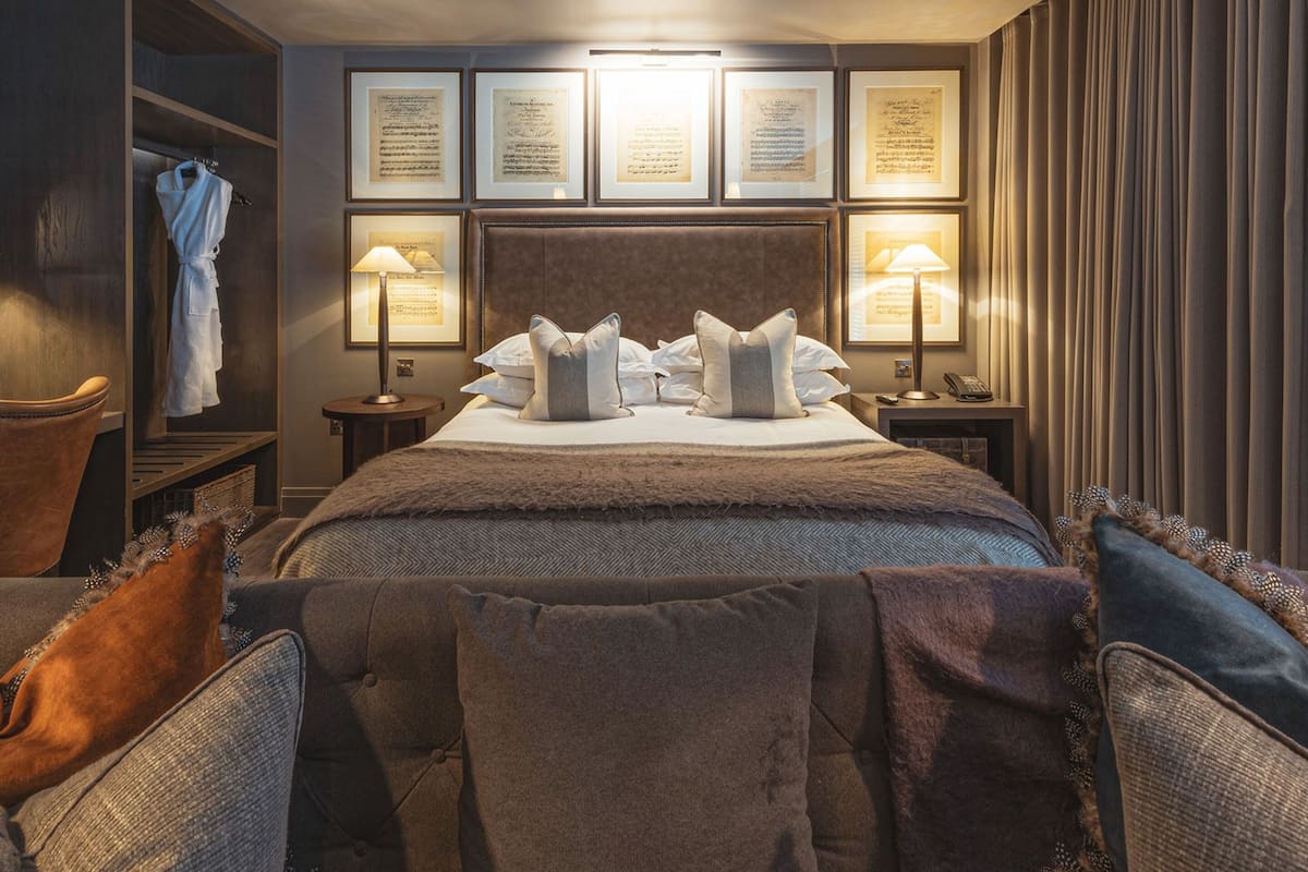 Habitación de hotel con una cama grande, dos mesitas de noche, un armario y certificados enmarcados en la pared.