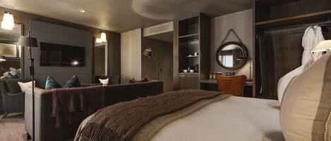 Une chambre d’hôtel moderne dotée d’un grand lit, d’un coin salon avec un canapé et un fauteuil, d’un bureau et d’une armoire.