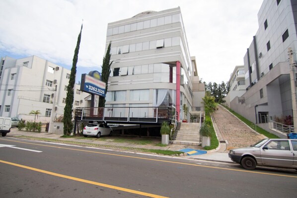 A multi-story building with a parking garage, a signboard, and a staircase leading to the entrance. - OYO Compacto Hotel Campinas (Campinas)