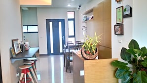 A modern hotel lobby with a reception desk, seating area, and a large plant. - Rainbowsea B&B (Huxi)