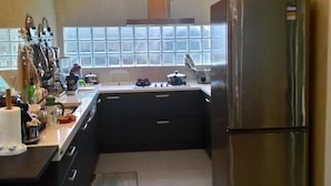 A modern kitchen with a stainless steel refrigerator, dark cabinetry, and a window providing natural light. - Rainbowsea B&B (Huxi)