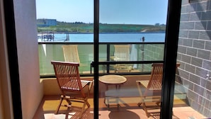 A balcony with two wooden chairs and a small table, overlooking a body of water and a distant shoreline. - Rainbowsea B&B (Huxi)