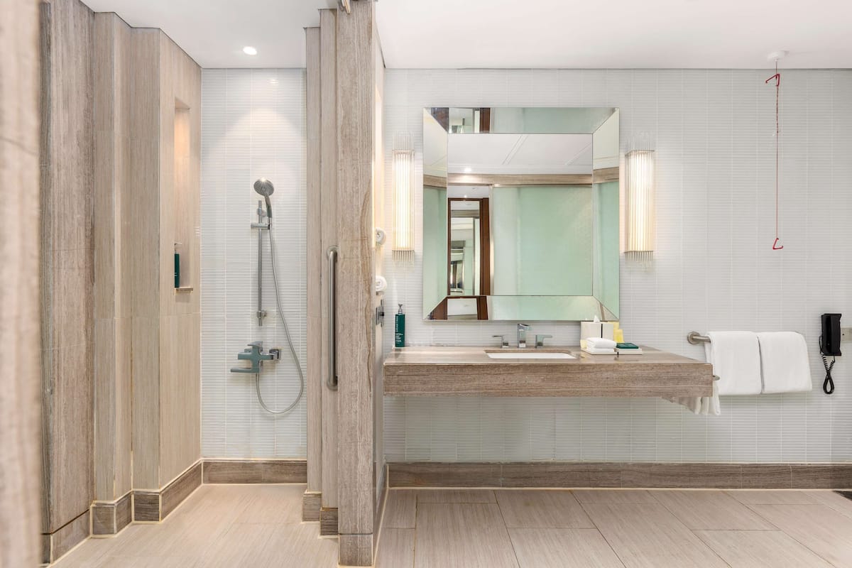 Un baño moderno con cabina de ducha de madera, un espejo grande y un tocador con lavamanos y toallero.