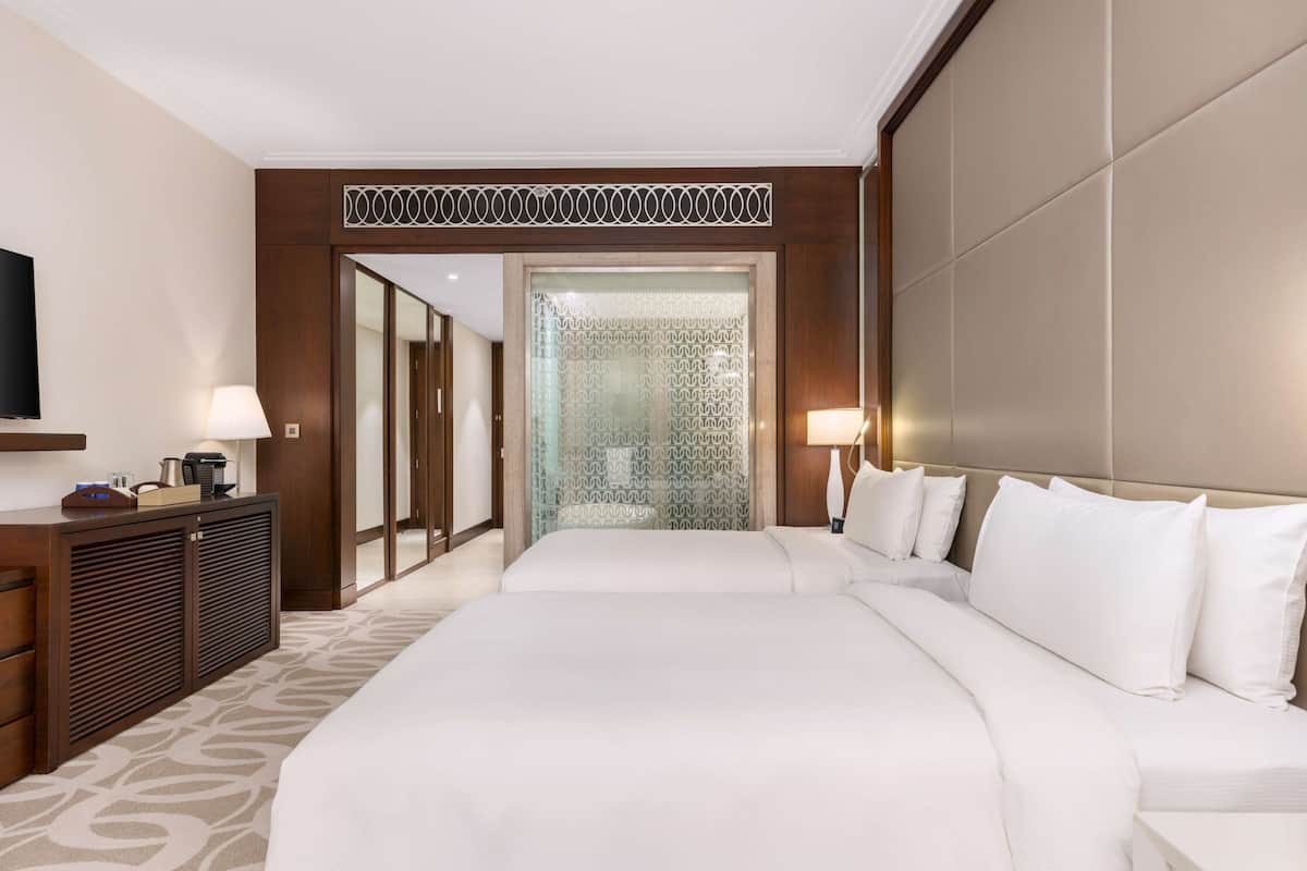 Habitación de hotel con una cama grande, un escritorio con lámpara, un televisor y un armario.
