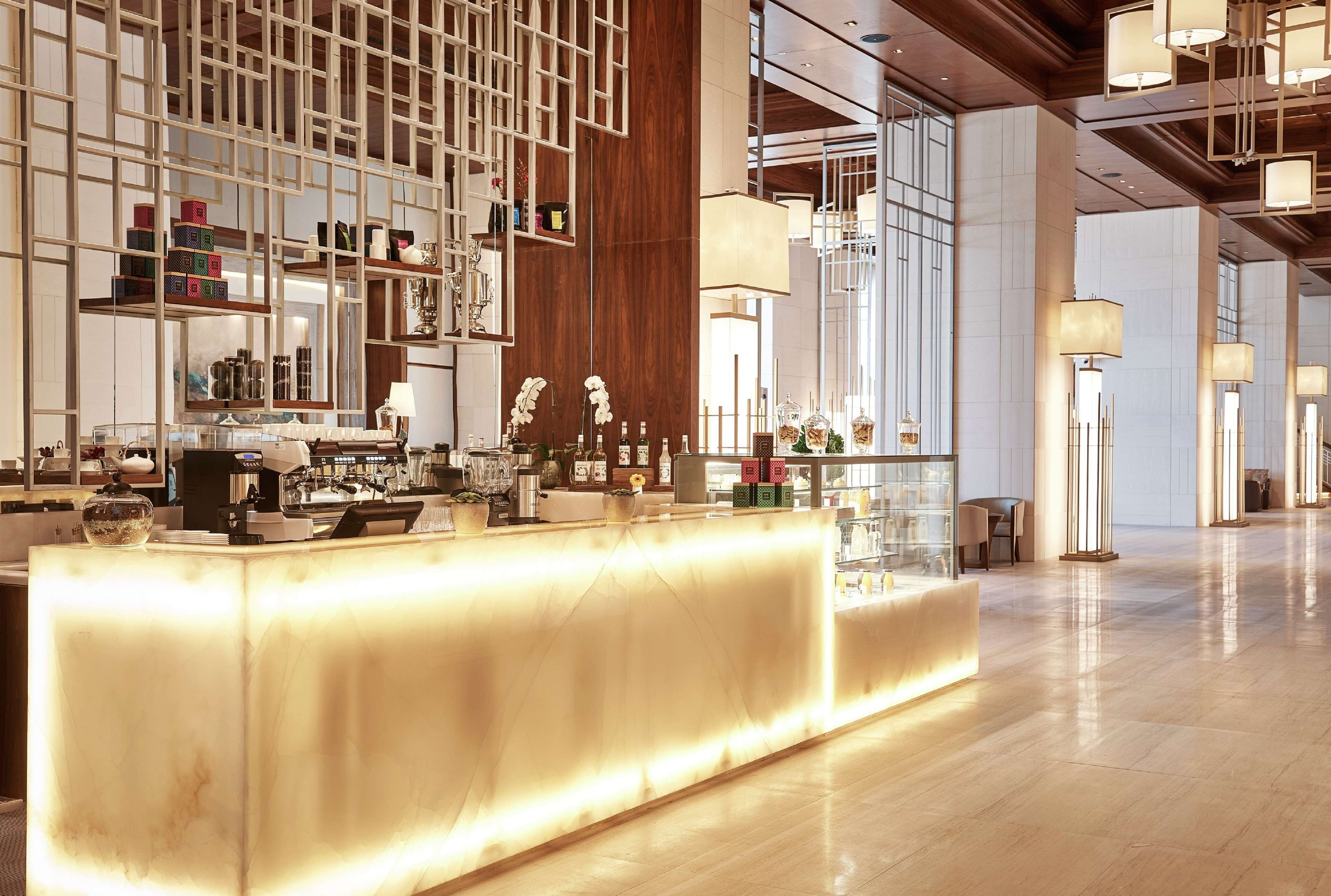 A modern hotel lobby with a reception desk, wooden paneling, and ambient lighting.