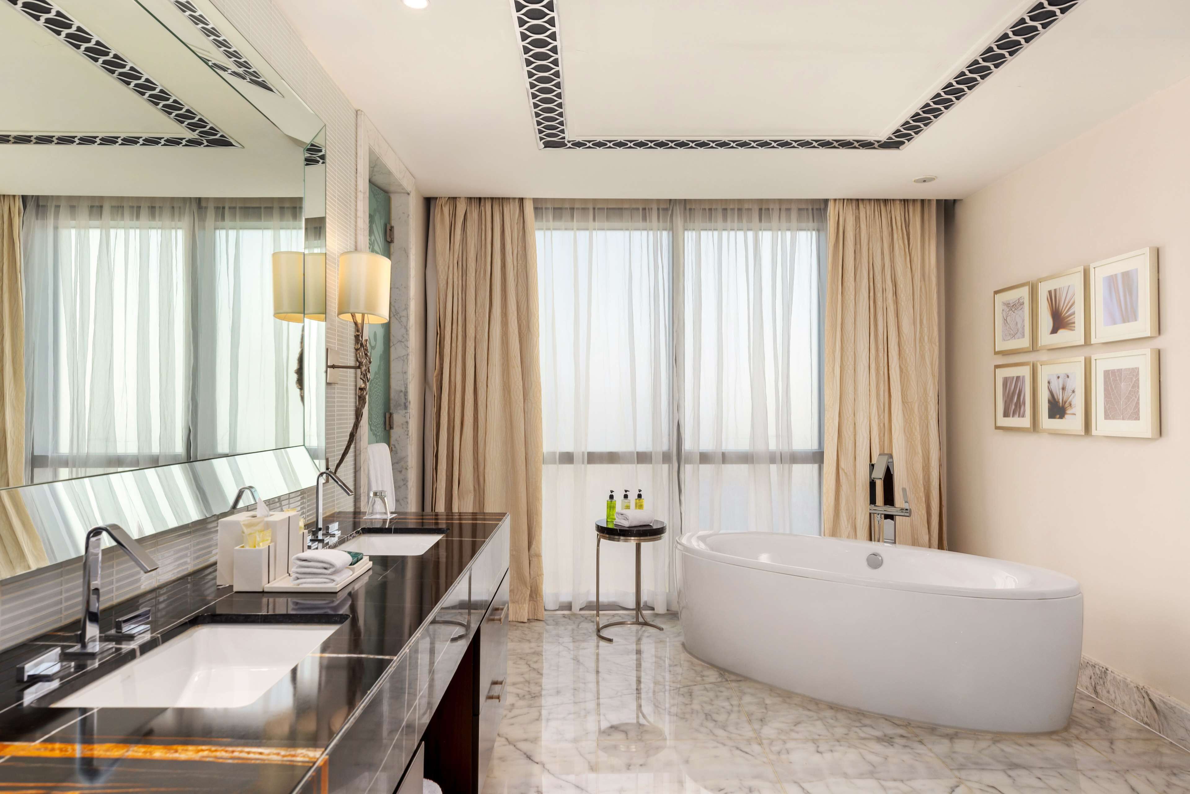 A modern bathroom with a large bathtub, dual sinks, and a vanity mirror.