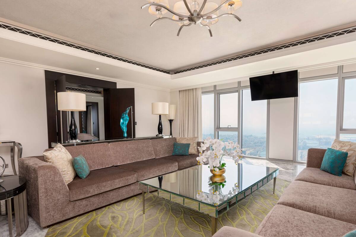 Una sala de estar moderna con un sofá, una mesa de centro de vidrio y un ventanal con vistas a la ciudad.
