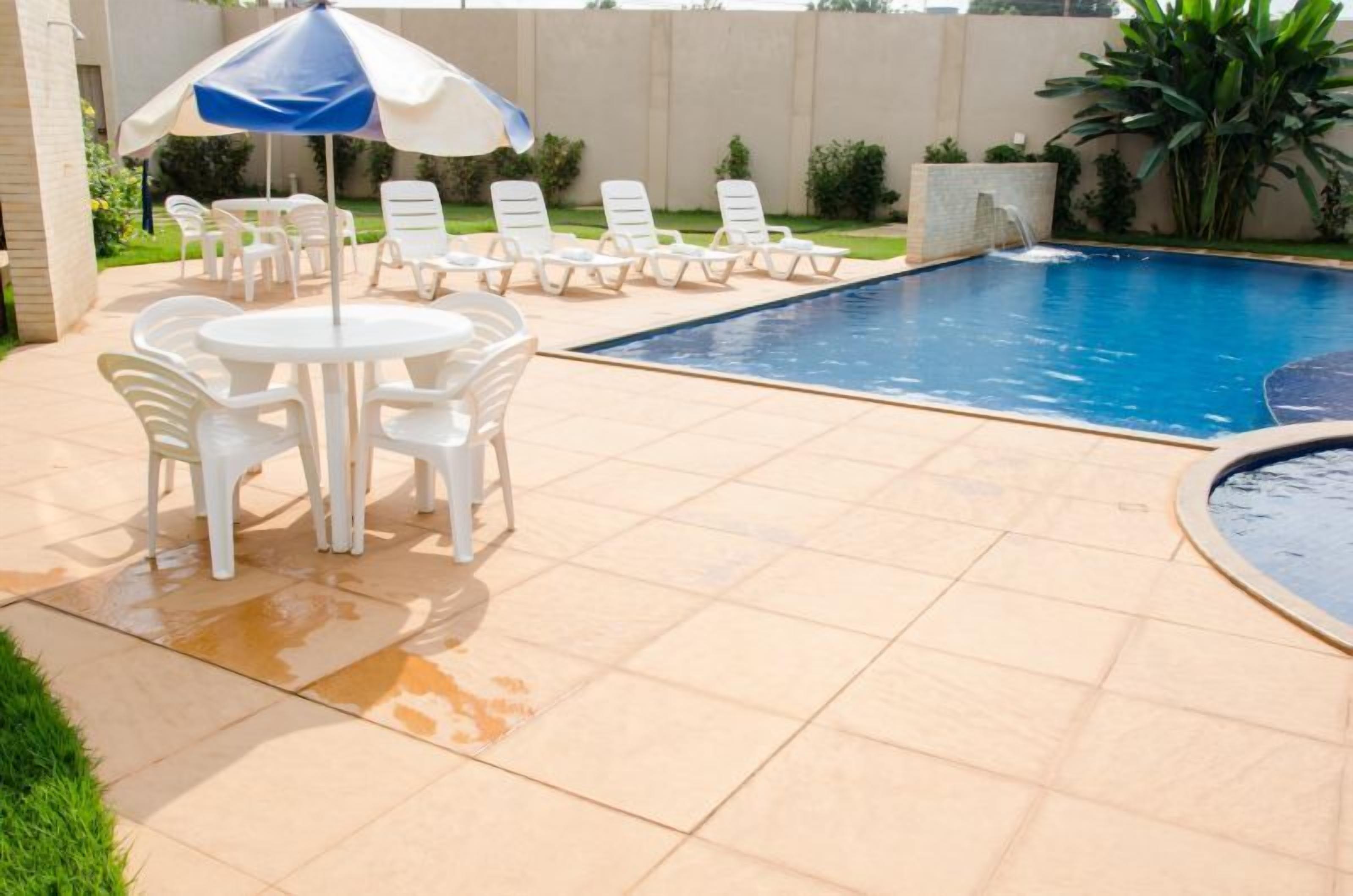 Ein Swimmingpool mit Liegestühlen und einem Tisch mit Sonnenschirm.