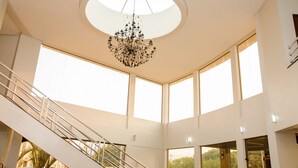 A spacious interior with a central chandelier, large windows, and a staircase. - eSuites Vale dos Carajás (Parauapebas)