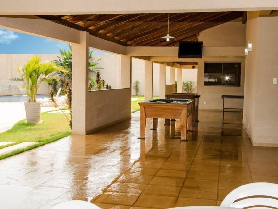 A covered patio with a pool, a wooden table, and potted plants.