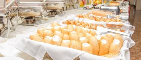 A buffet setup with various food items, including bread and pastries, arranged on tables.