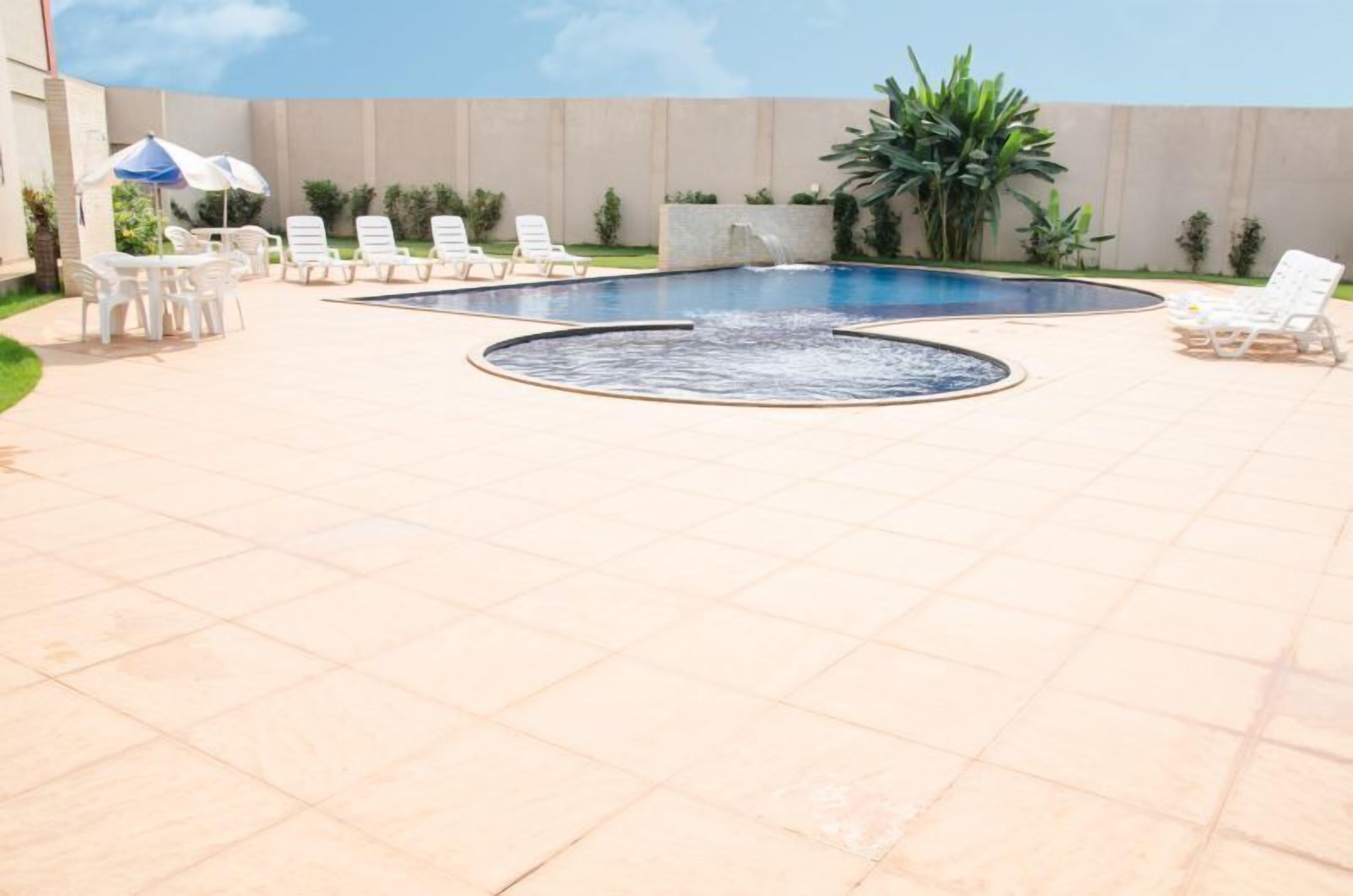 A swimming pool with lounge chairs and a table with umbrellas.