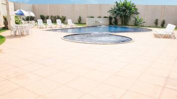 A swimming pool with lounge chairs and a table with umbrellas.