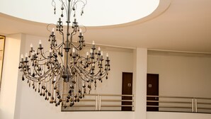 A grand chandelier in a spacious lobby with a high ceiling and a balcony railing. - eSuites Vale dos Carajás (Parauapebas)