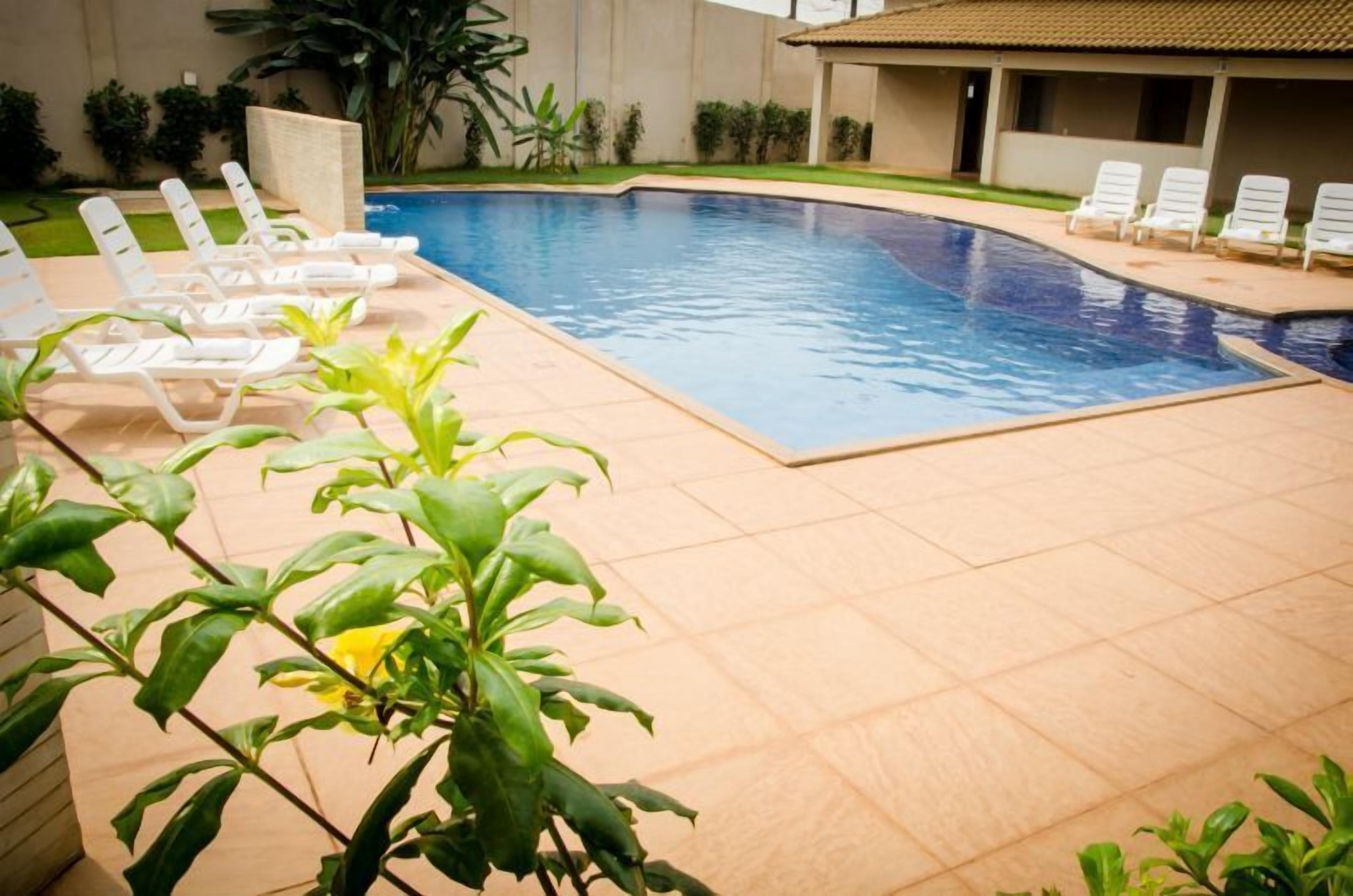 A swimming pool with lounge chairs and a tiled deck.