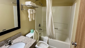 A bathroom with a granite sink, toilet, and shower. - American Inn (Alexander City)