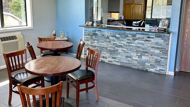 A dining area with a stone counter and wooden chairs. - American Inn (Alexander City)