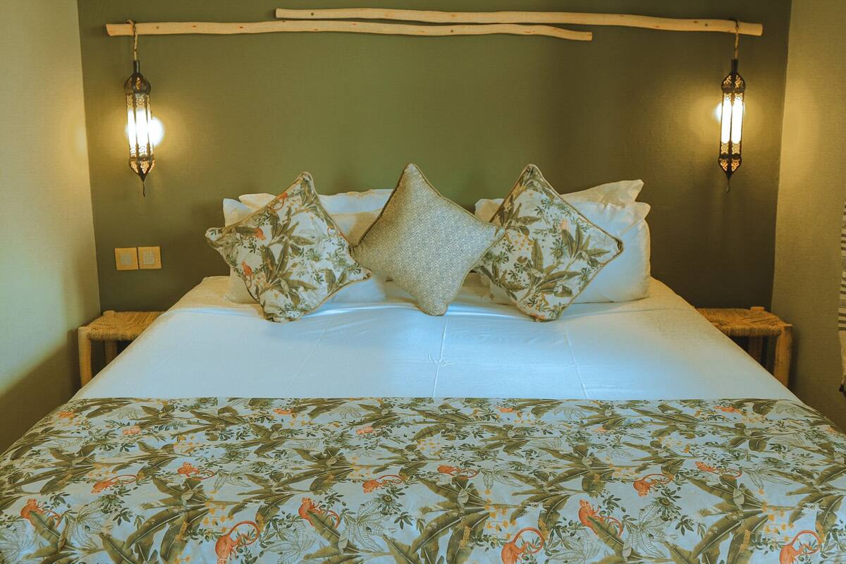 A bed with floral-patterned bedding, two nightstands, and two wall-mounted lamps.