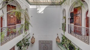 A courtyard with white walls, wooden doors, and balconies with wrought iron railings and hanging plants. - Riad Clefs D'orient (Marrakech)