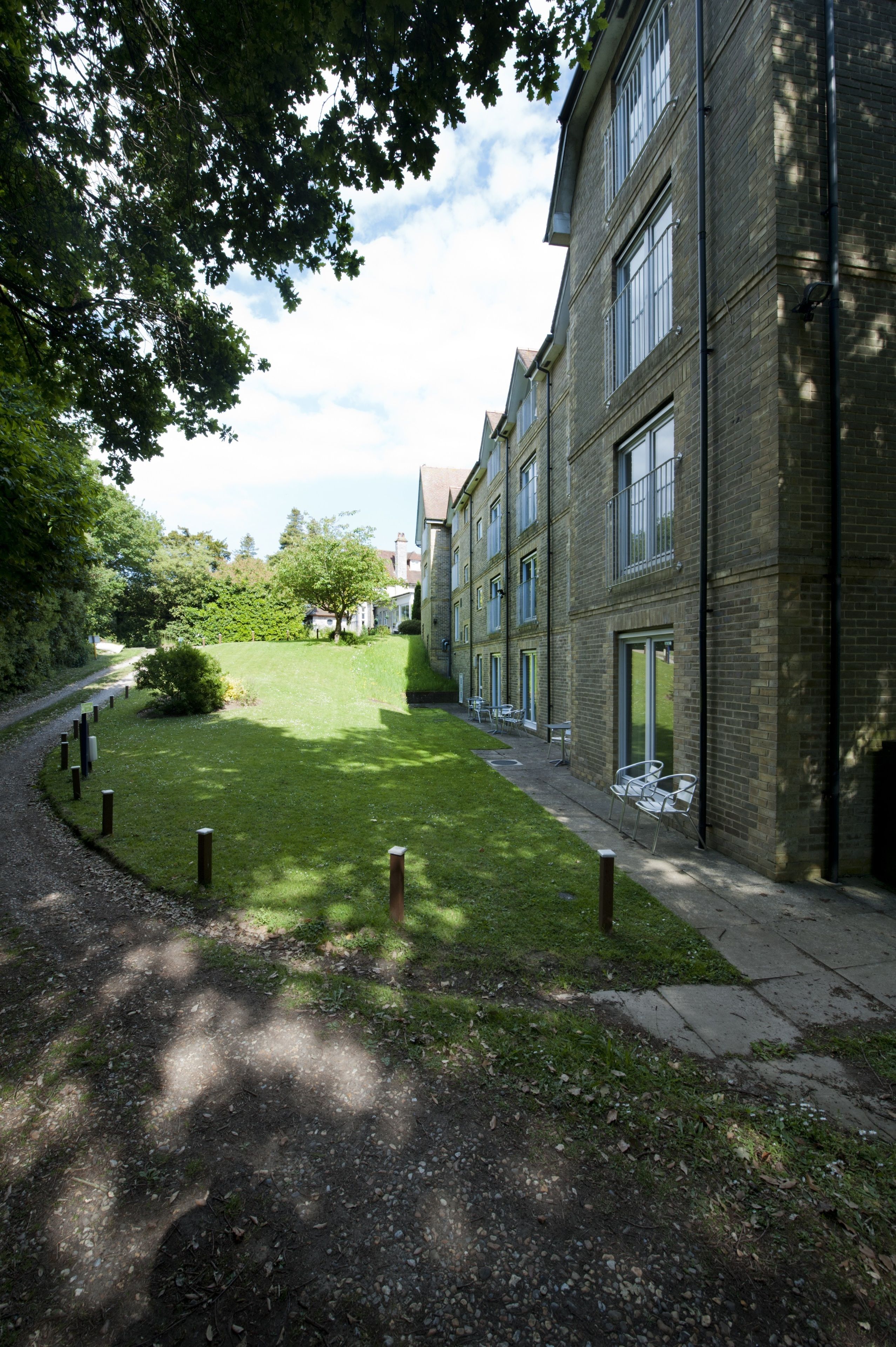 A courtyard with a pathway leading to a building with multiple windows and doors.