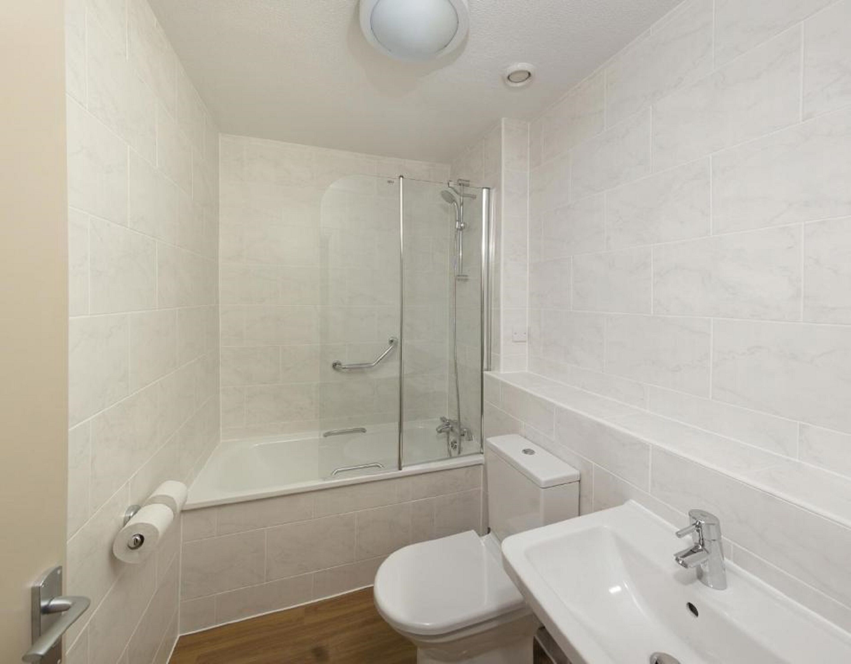 A bathroom with a glass-enclosed shower, a toilet, and a sink.