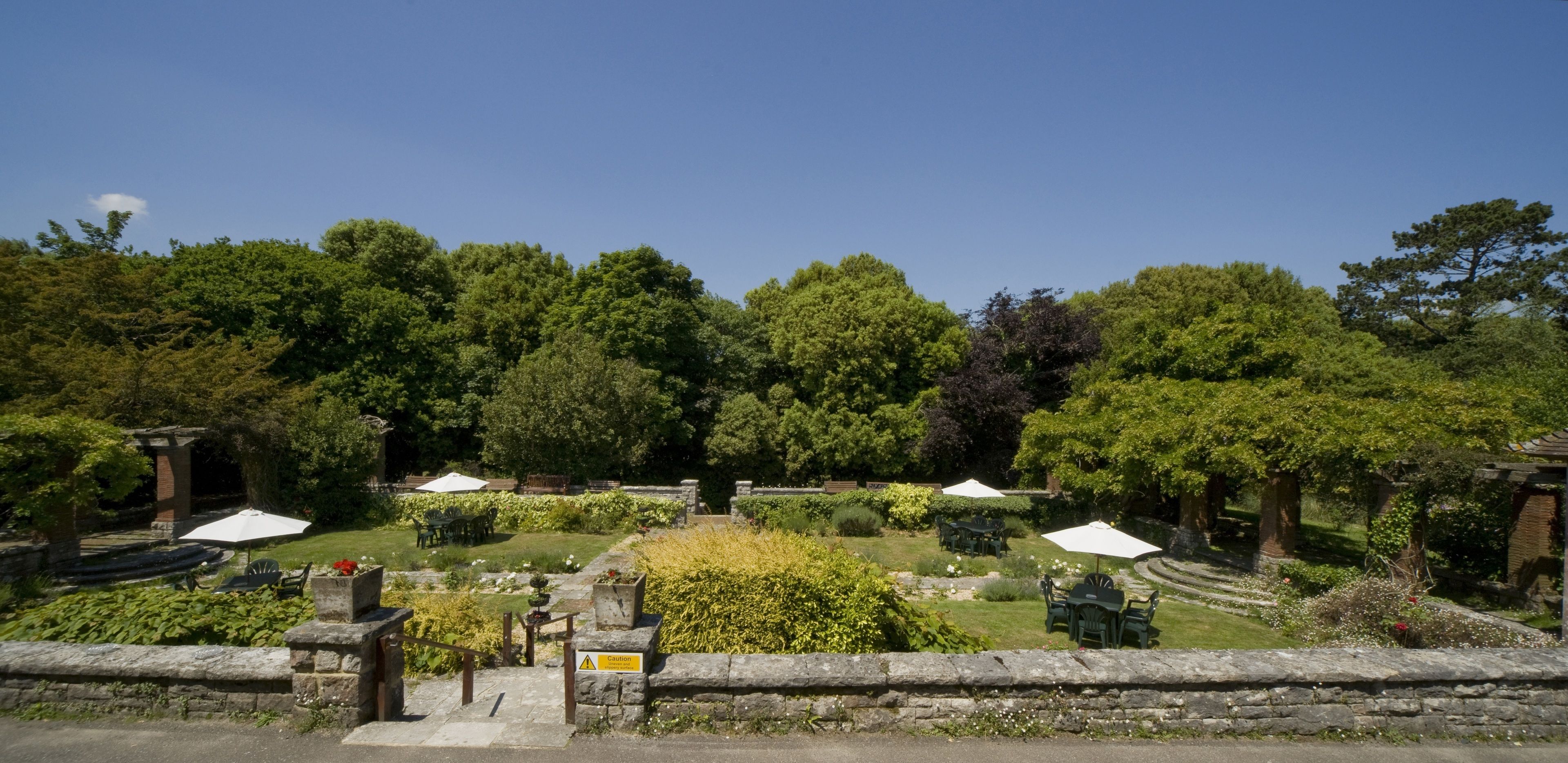 A garden with stone pathways, outdoor seating, and lush greenery.