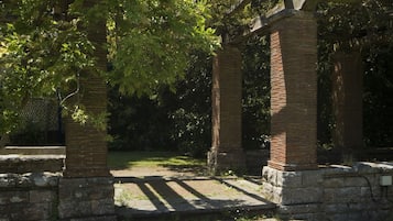 Een stenen, ronde constructie met een zuilvormige steunstructuur van baksteen, omgeven door begroeiing en bomen.