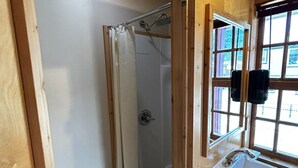 Un baño con ducha, lavamanos y ventana.