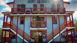 Un edificio de dos pisos con un balcón en el piso superior, un letrero que dice "The Bunk House Hotel" y una escalera que conduce a la entrada.