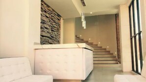 A modern interior with a white sofa, a stone accent wall, and a staircase leading to an upper level.