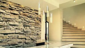A modern reception area with a stone wall, a marble counter, and a staircase.